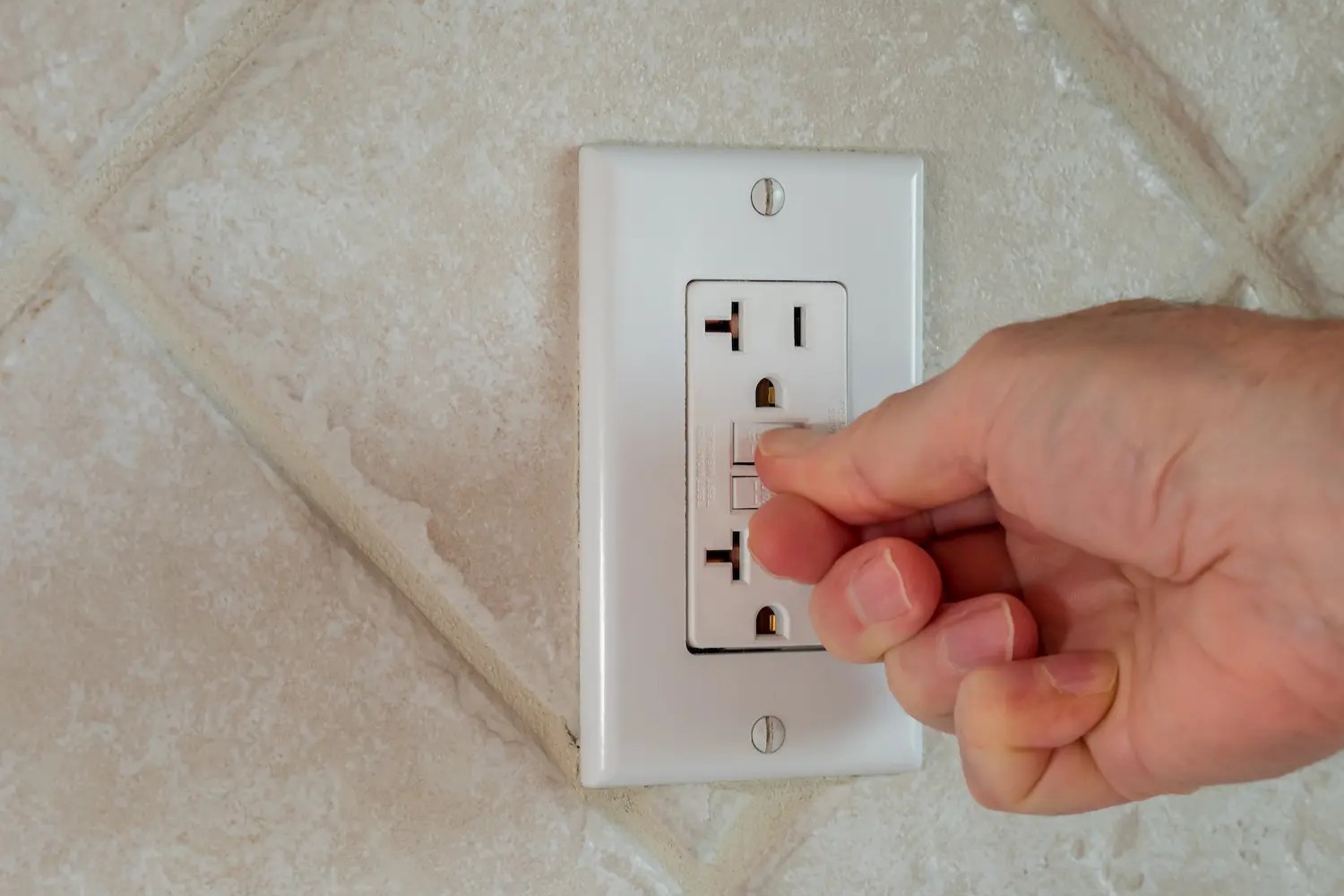 A homeowner pressing the GFCI button on an outlet