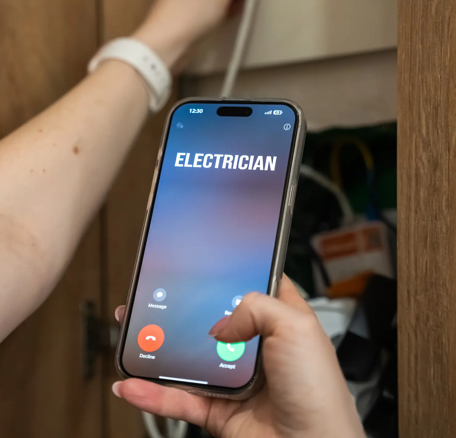 WA homeowner calling an electrician on their phone while checking breaker panel